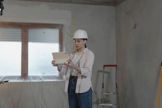 gros plan sur des mains tenant une tablette affichant un formulaire de demande de devis, avec en arrière-plan un chantier de rénovation en cours dans une maison lumineuse