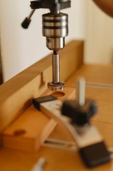 gros plan sur un axe en acier inoxydable inséré dans un tube de cuivre encastré dans une lame de bois en atelier, perceuse posée à côté