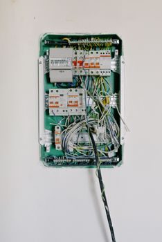 gros plan sur un tableau électrique ancien avec plusieurs fusibles en porcelaine blanche montés sur une plaque de fibrociment, fils électriques apparents et légèrement noircis autour d'un contact