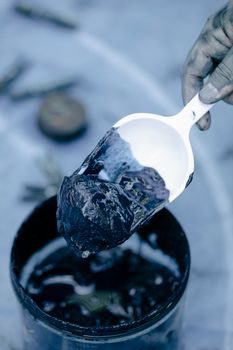 main gantée grattant délicatement un nid de terre séché sur un rebord de fenêtre à l'aide d'une spatule