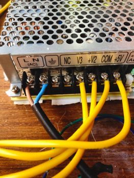 bornier de raccordement à l'arrière d'une cuisinière électrique avec trois fils phase neutre terre visibles et vis desserrées